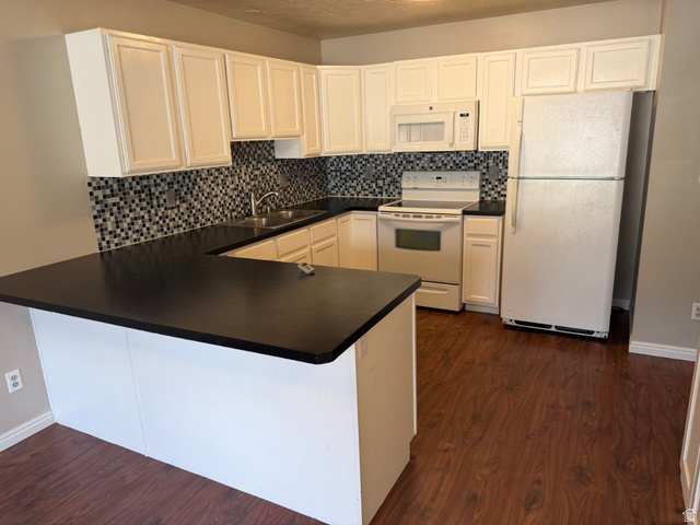 1563 South 600 East Springville, UT 84663 - Photo 10 of 30 U-shaped kitchen featuring white cabinetry, dark countertops, a mosaic tile backsplash, and wood-finish flooring