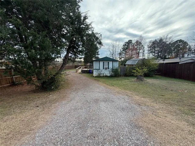 a view of a house with a yard and large trees