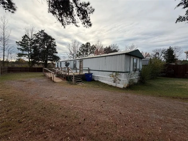 a view of a backyard with large trees and wooden fence