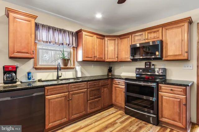 a kitchen with stainless steel appliances granite countertop wooden cabinets and a sink