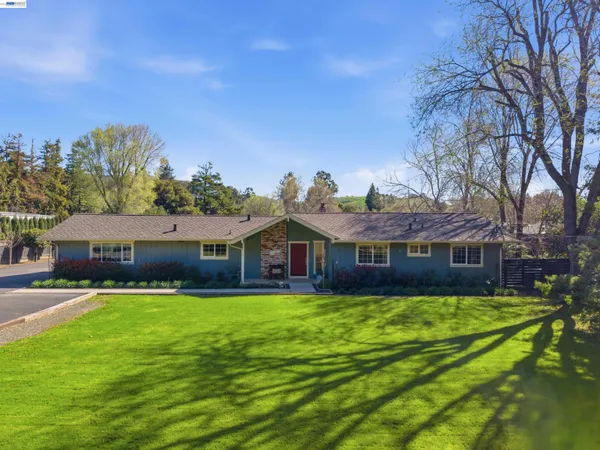 a view of a house with a big yard and large trees