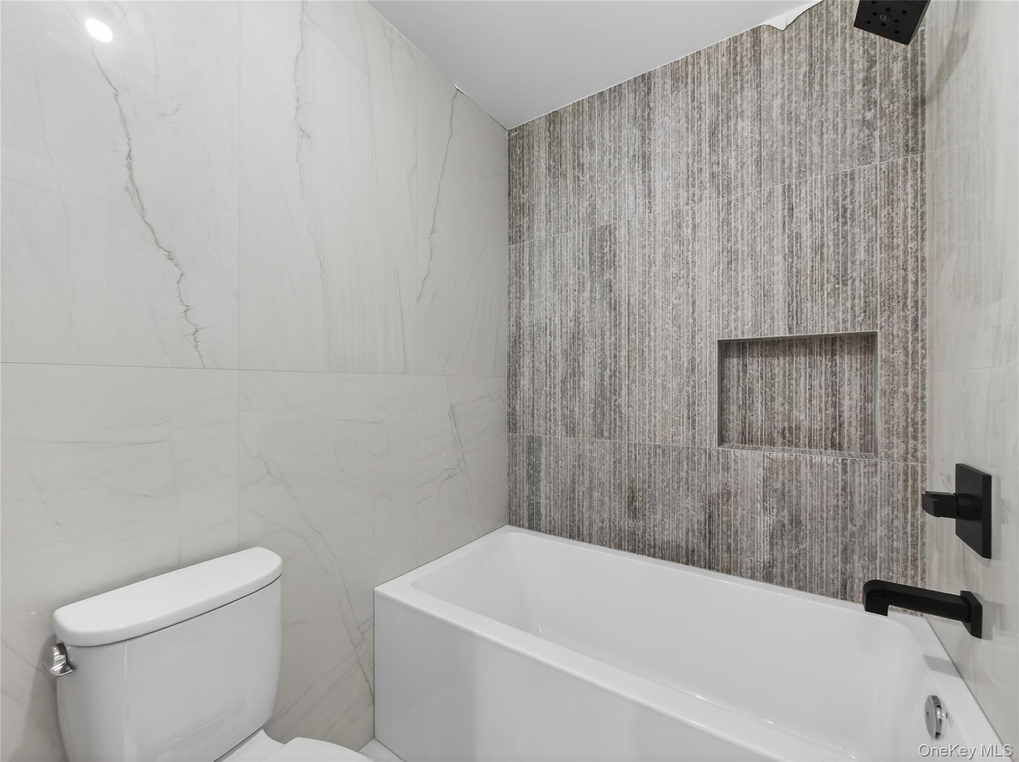 13 Elener Lane, Unit 202 Spring Valley, NY 10977 - Photo 34 of 48 a bathroom with a white bath tub and a toilet