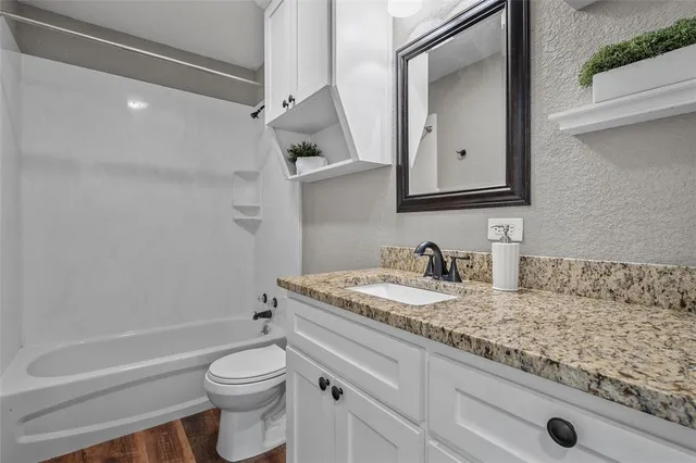 a bathroom with a granite countertop sink toilet and shower