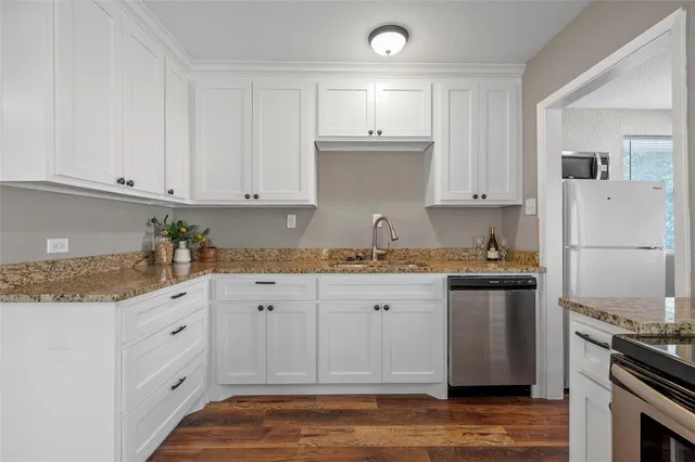 a kitchen with granite countertop white cabinets and stainless steel appliances