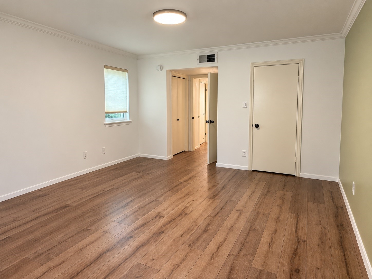 3500 Tangle Brush Drive, Unit 65 Spring, TX 77381 - Photo 13 of 20 Generously sized primary bedroom features warm wood-look flooring, crown molding, a neutral color palette, and natural light, with plenty of flexibility for a full bedroom suite and additional furnishings.