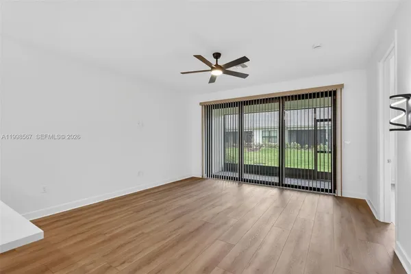 an empty room with wooden floor fan and windows