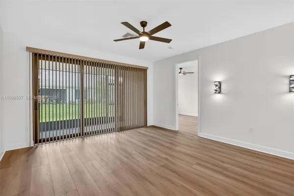 a view of a room with wooden floor and a ceiling fan