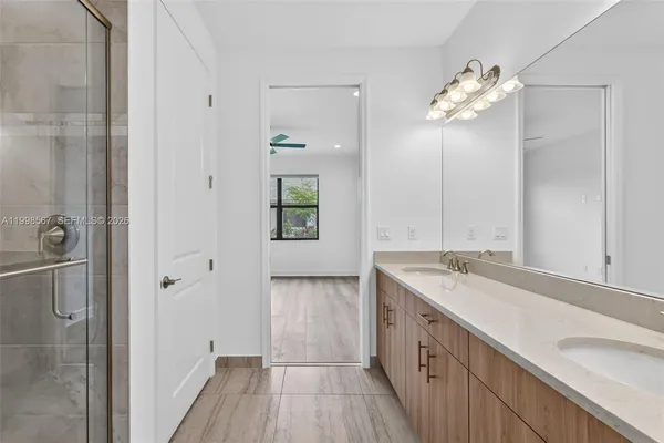 a spacious bathroom with a granite countertop sink a mirror and a shower