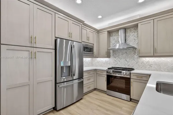 a kitchen with cabinets stainless steel appliances and wooden floor