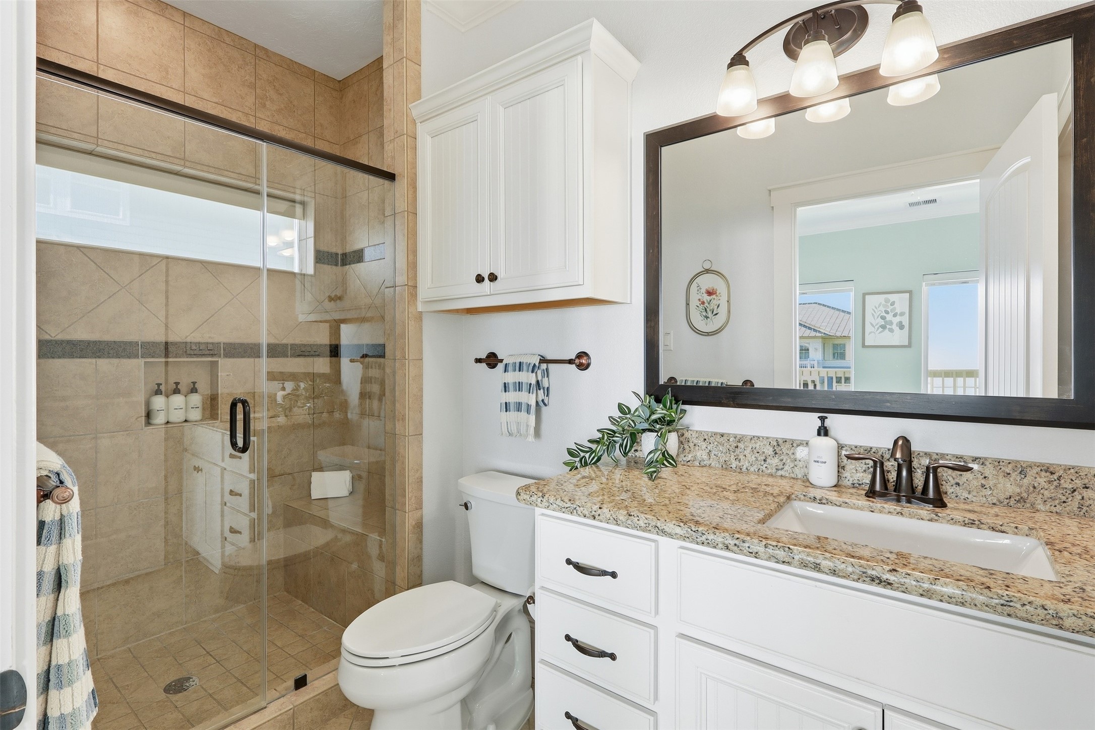 11622 Beachside Galveston, TX 77554 - Photo 18 of 39 This bathroom features a spacious glass-enclosed shower, a granite countertop with a built-in sink, and elegant dark fixtures.