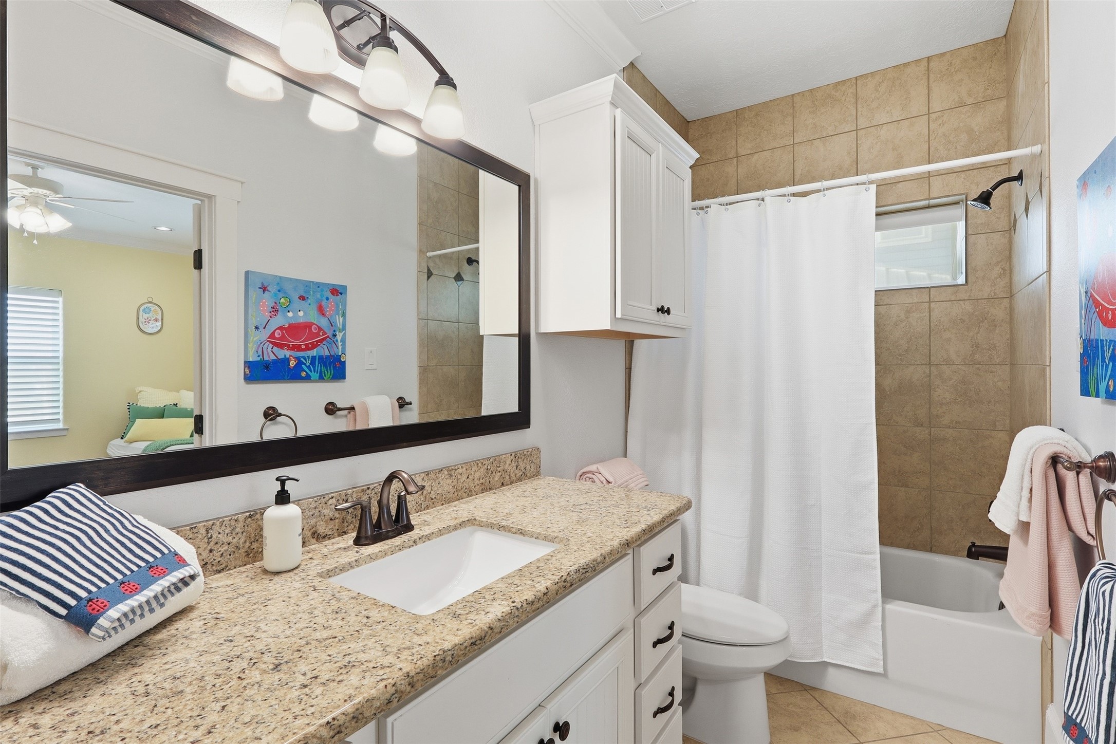 11622 Beachside Galveston, TX 77554 - Photo 21 of 39 This bathroom features a polished granite countertop, a large mirror, and modern lighting. It includes a bathtub with a tiled shower area.