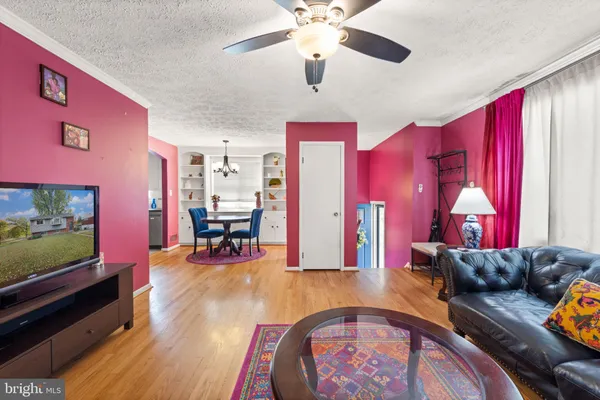 a living room with furniture a dining table and paintings on the wall with wooden floor