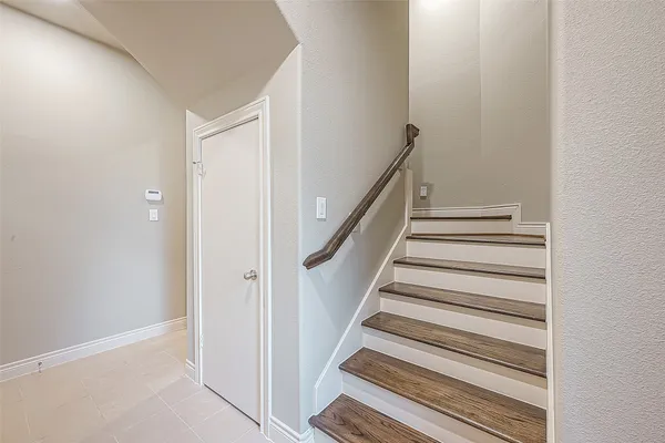 a view of staircase with railing and white walls