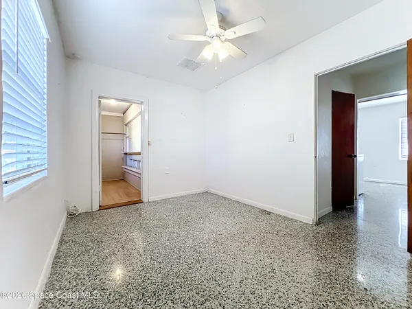 an empty room with closet and a ceiling fan