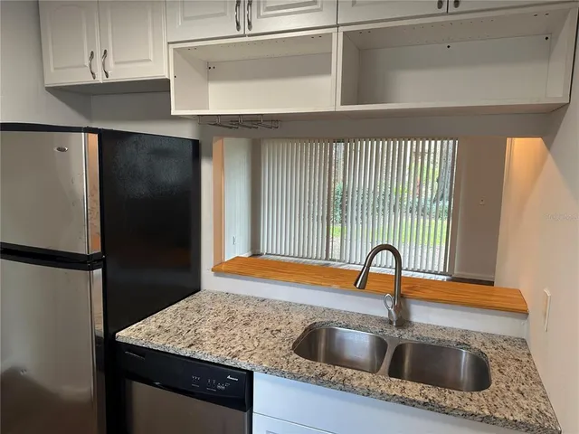 a kitchen with a sink a refrigerator and cabinets