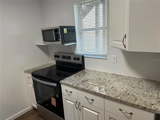 a kitchen with granite countertop a sink a stove and cabinets