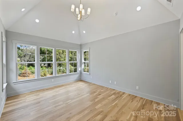 a view of an empty room with a window and hardwood floor