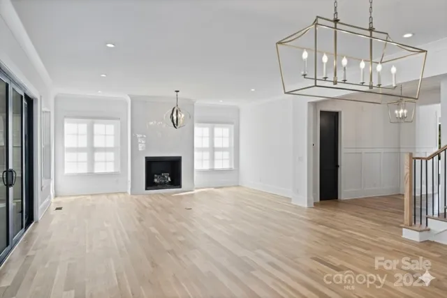 a view of an empty room with wooden floor fireplace and a window