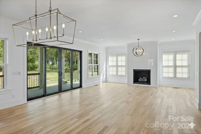 a view of an empty room with wooden floor fireplace and a window