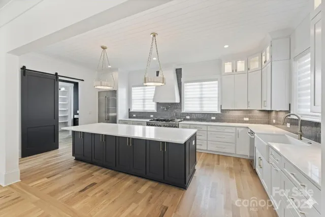 a large kitchen with a large counter top a sink stainless steel appliances and cabinets