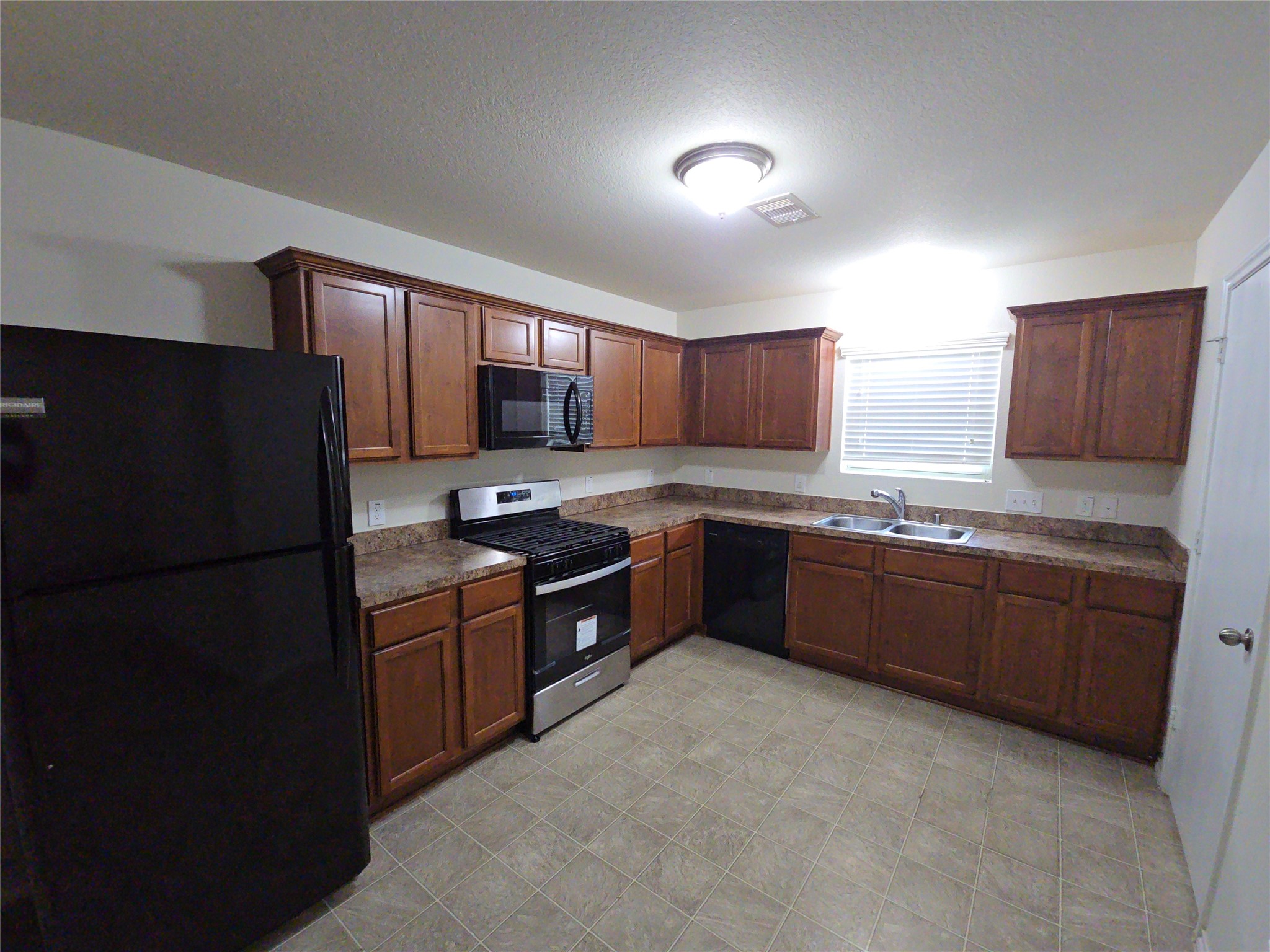 810 Lightningbug Lane Conroe, TX 77301 - Photo 4 of 27 a kitchen with granite countertop wooden cabinets a refrigerator and a sink