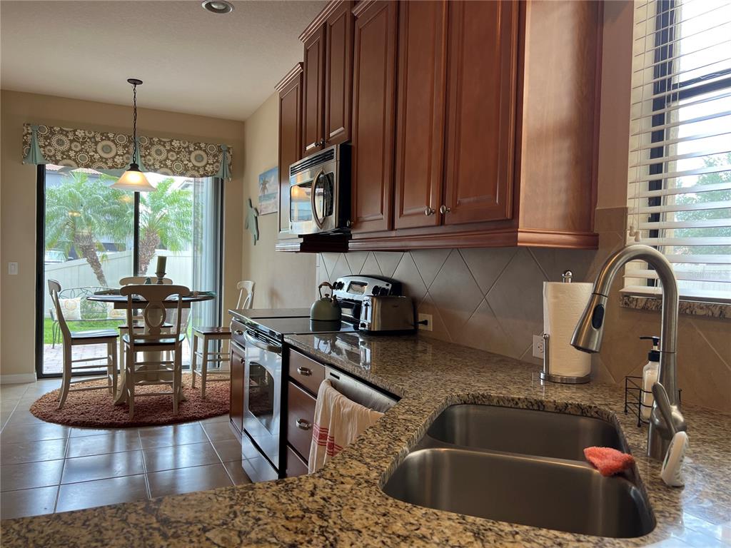 2002 Fishtail Fern Way Ocoee, FL 34761 - Photo 13 of 51 a kitchen with stainless steel appliances granite countertop a sink a stove and a wooden cabinets