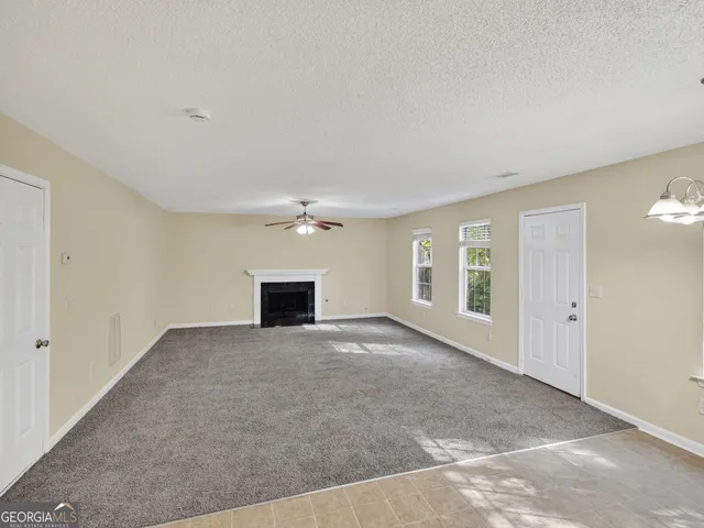 an empty room with windows and fireplace
