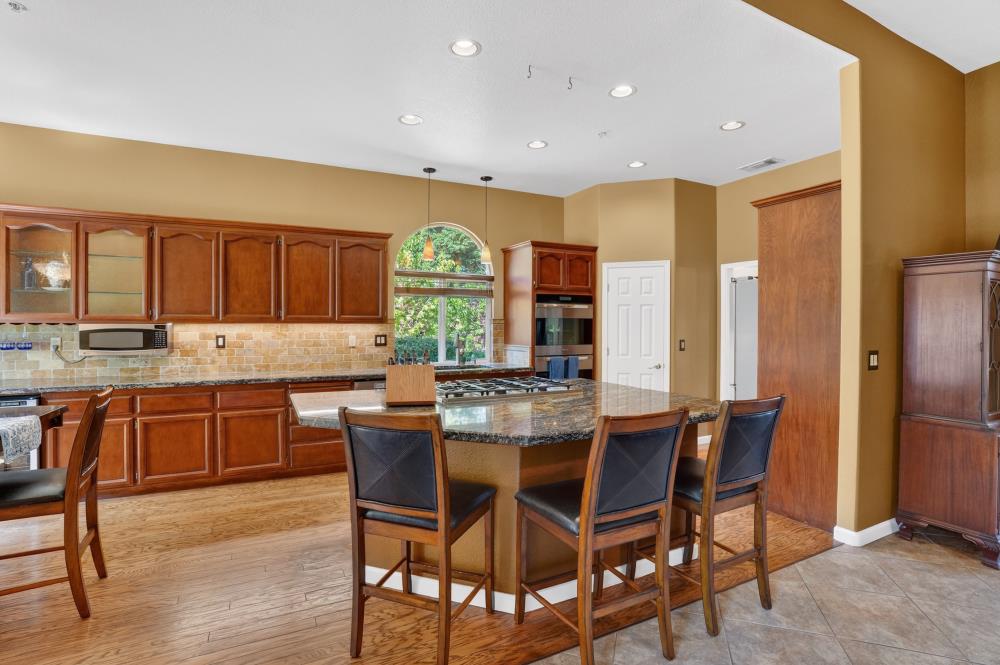 6504 Swallowsview Court Rocklin, CA 95677 - Photo 13 of 66 a kitchen with stainless steel appliances granite countertop wooden floor cabinets dining table and chairs