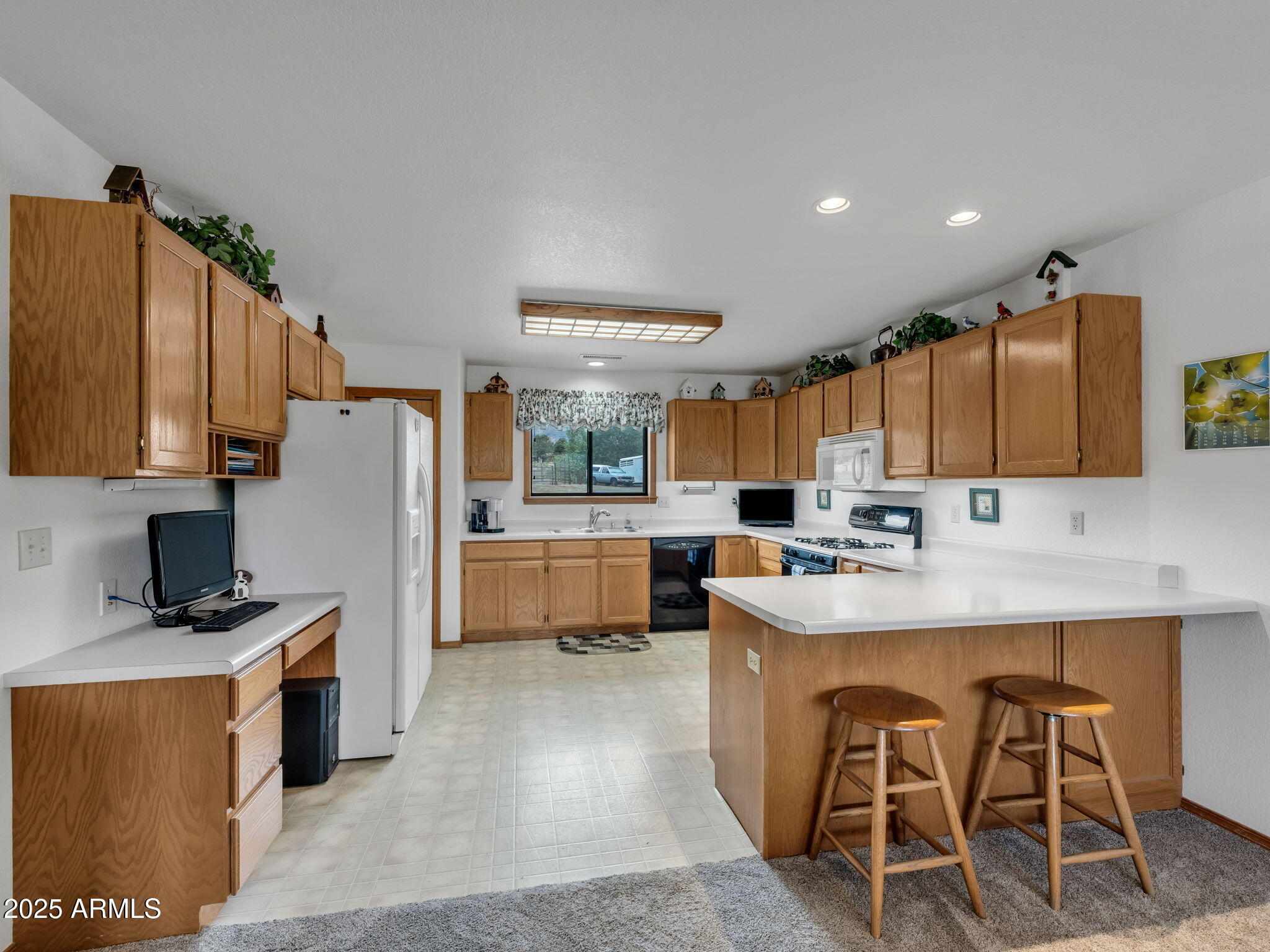 5545 East Atkinson Road Flagstaff, AZ 86004 - Photo 13 of 55 a kitchen with stainless steel appliances kitchen island granite countertop a refrigerator a stove and a sink with wooden cabinets