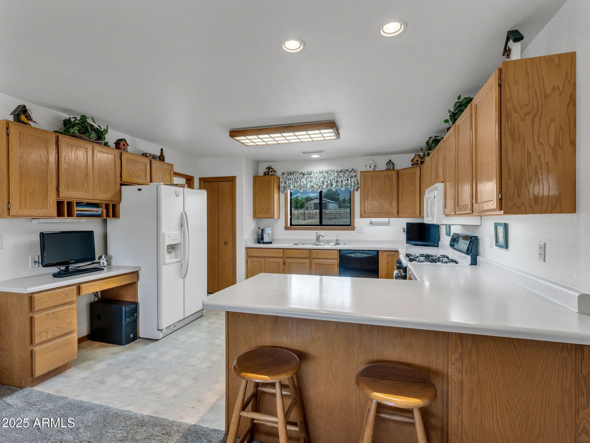 5545 East Atkinson Road Flagstaff, AZ 86004 - Photo 15 of 55 a kitchen with stainless steel appliances a sink a stove a refrigerator cabinets and a counter top space
