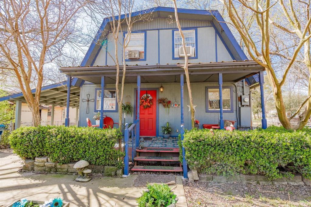 Front facade with a covered porch, blue trim accents, red entry door, and dormer windows