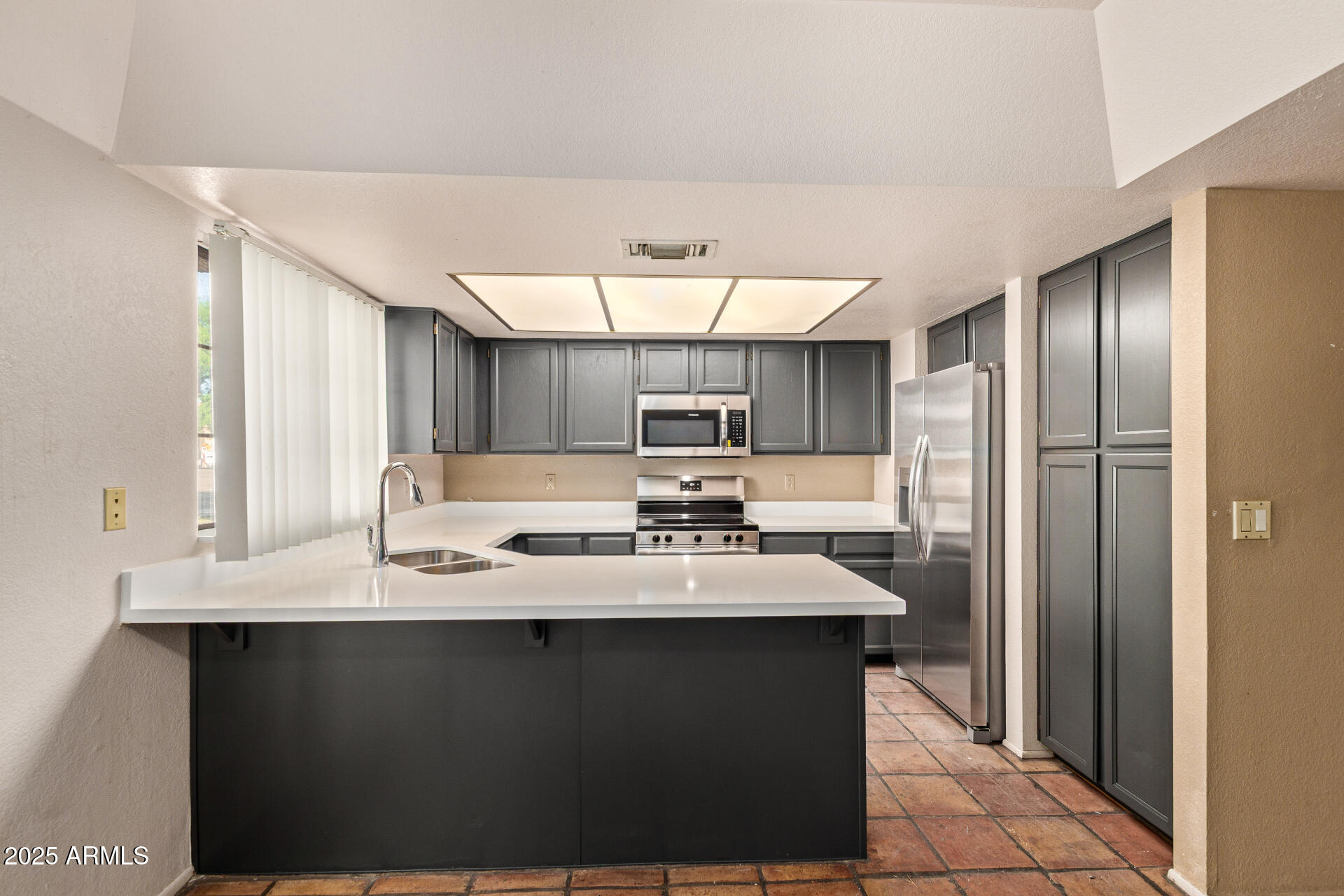 609 East Mesquite Circle, Unit D131 Tempe, AZ 85288 - Photo 8 of 39 a kitchen with kitchen island granite countertop a sink stainless steel appliances and cabinets