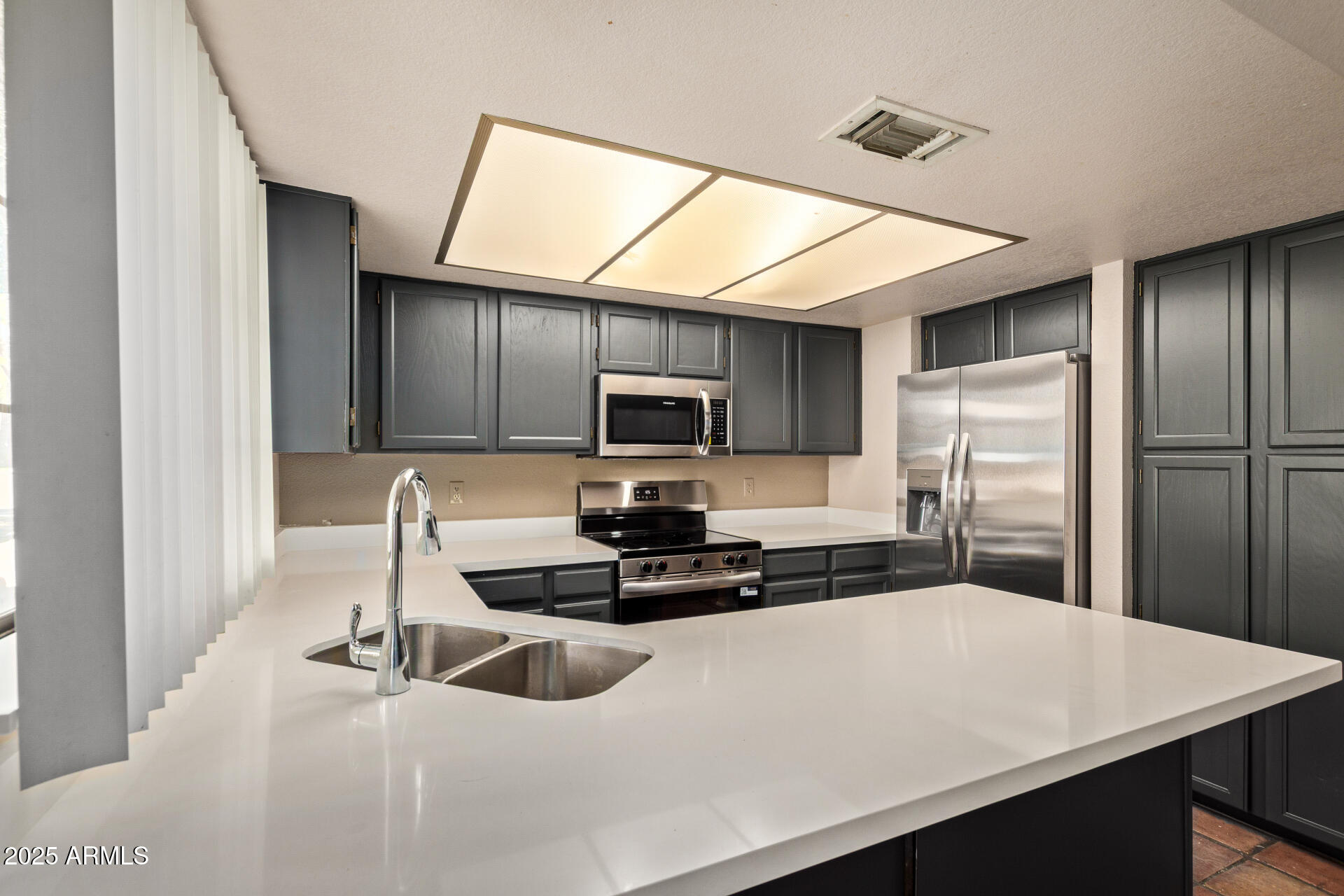 609 East Mesquite Circle, Unit D131 Tempe, AZ 85288 - Photo 9 of 39 a kitchen with stainless steel appliances a refrigerator sink microwave and stove
