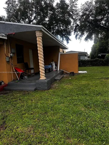 a view of backyard with barbeque grill and a large tree
