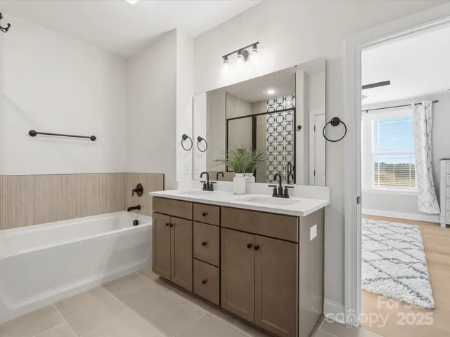 a bathroom with a bathtub a double vanity sink and mirror