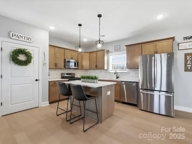 a kitchen with stainless steel appliances granite countertop a refrigerator a sink dishwasher a stove and a refrigerator with wooden floor