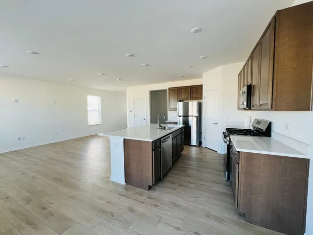 a large kitchen with stainless steel appliances granite countertop a lot of counter space and wooden floor