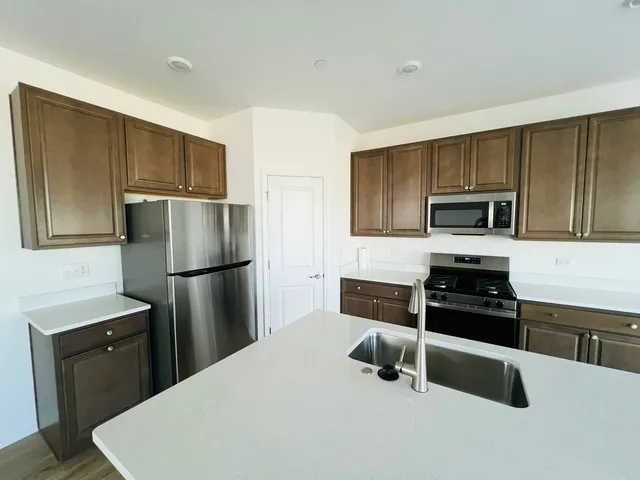 a kitchen with a refrigerator a microwave a sink and cabinets
