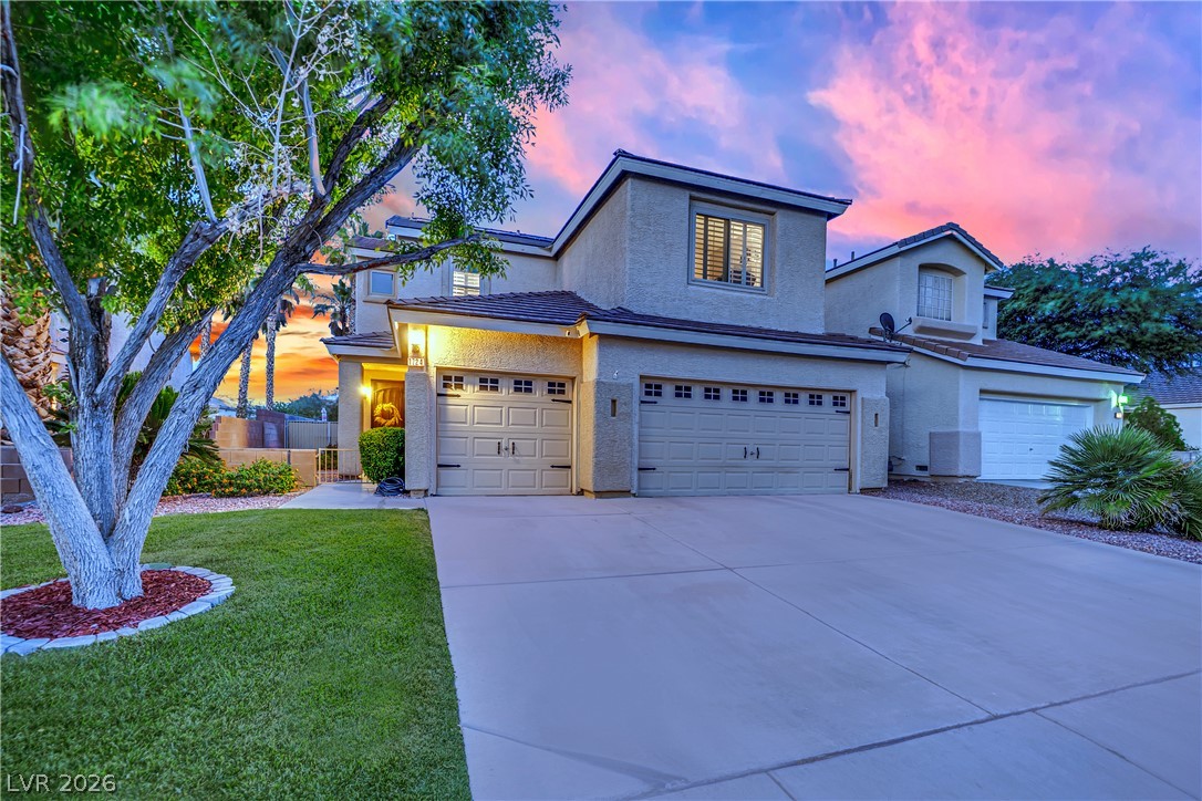 1724 Millstream Way Henderson, NV 89074 - Photo 42 of 60 A well-maintained residence with a multi-car garage, manicured lawn, and beautiful evening sky.