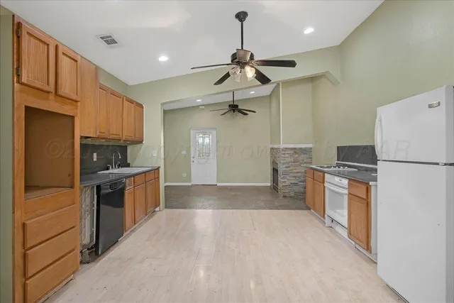 a kitchen with granite countertop a refrigerator oven a sink and dishwasher