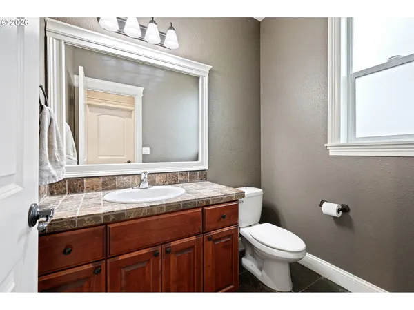 a bathroom with a granite countertop toilet a sink a mirror and a window