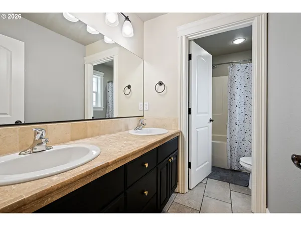 a bathroom with a granite countertop sink a mirror and a shower