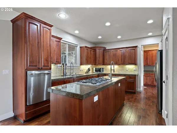 a kitchen with kitchen island granite countertop wooden cabinets a refrigerator and a stove