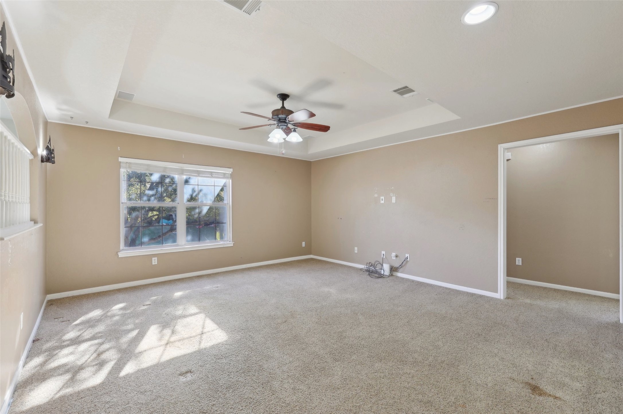 2948 Grimes Ranch Road Austin, TX 78732 - Photo 27 of 40 Spacious room featuring a tray ceiling with a ceiling fan, recessed lighting, and a large window.