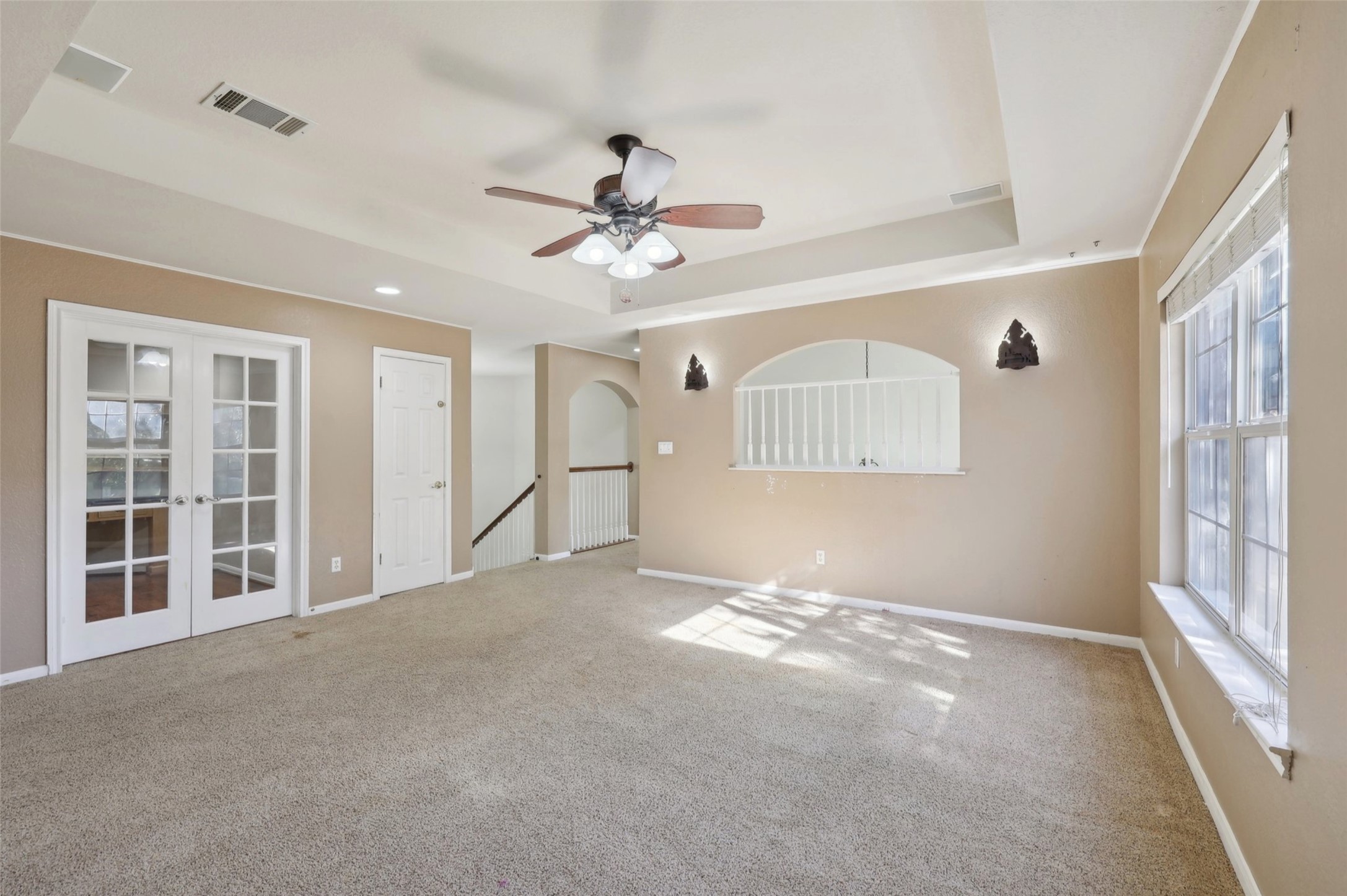2948 Grimes Ranch Road Austin, TX 78732 - Photo 28 of 40 Spacious room featuring a tray ceiling with a ceiling fan, French doors with glass panes, and a large window providing natural light.