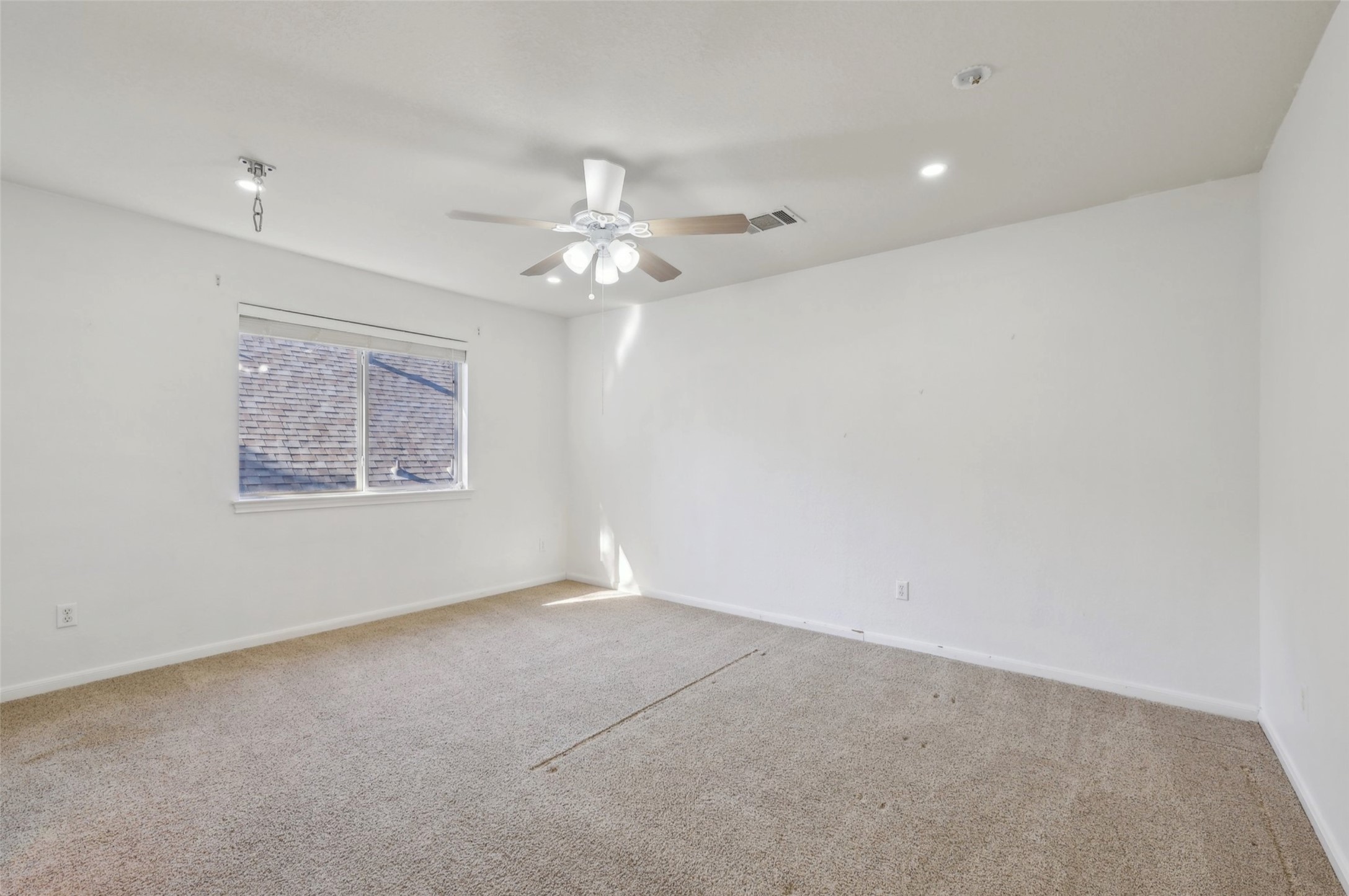 2948 Grimes Ranch Road Austin, TX 78732 - Photo 30 of 40 Spacious room featuring neutral carpeting, a large window, a ceiling fan with light fixture, and recessed lighting.