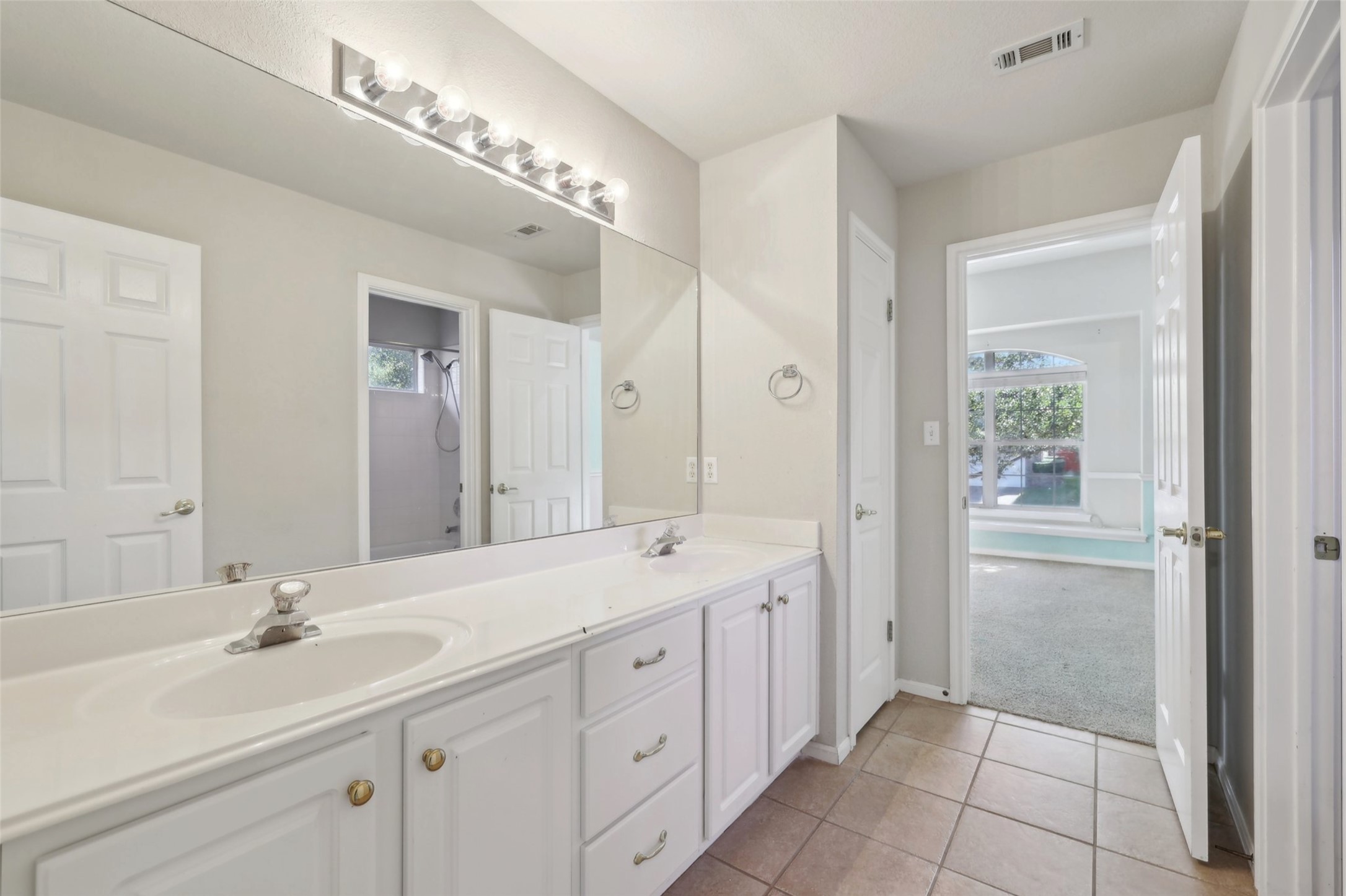 2948 Grimes Ranch Road Austin, TX 78732 - Photo 32 of 40 Bathroom with dual vanity featuring white cabinetry, integrated sinks, a full-width mirror, and overhead strip lighting.
