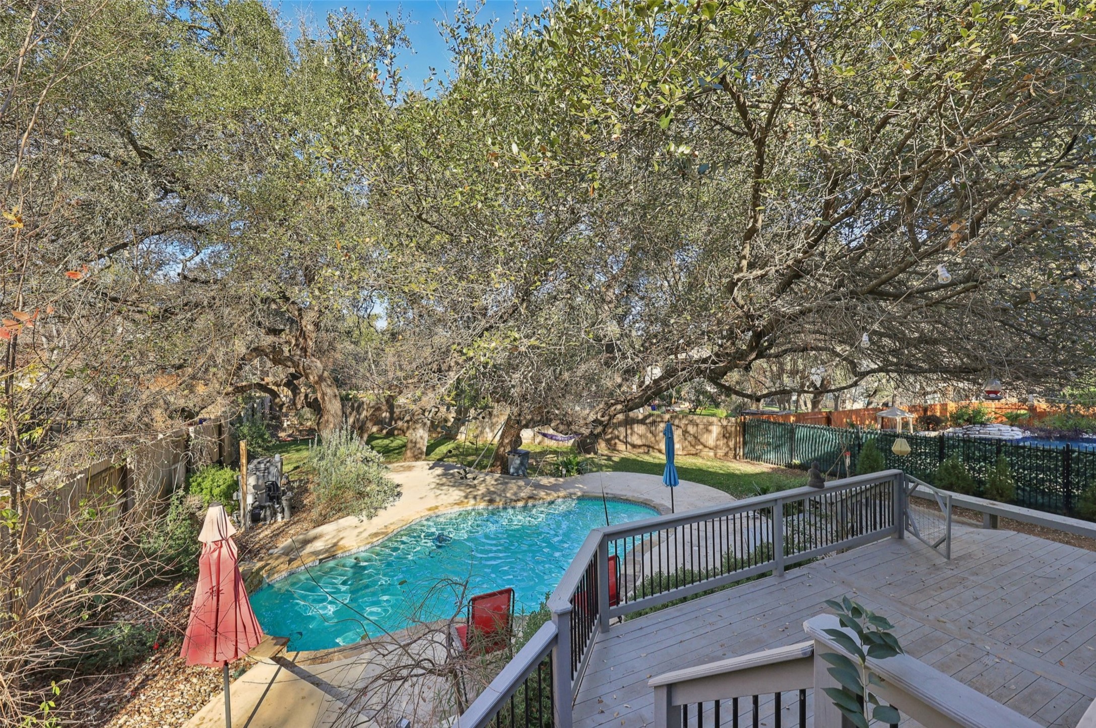 2948 Grimes Ranch Road Austin, TX 78732 - Photo 37 of 40 Expansive outdoor space featuring a multi-level wood deck with railings, a built-in swimming pool with concrete surround, mature trees, and a fenced perimeter.