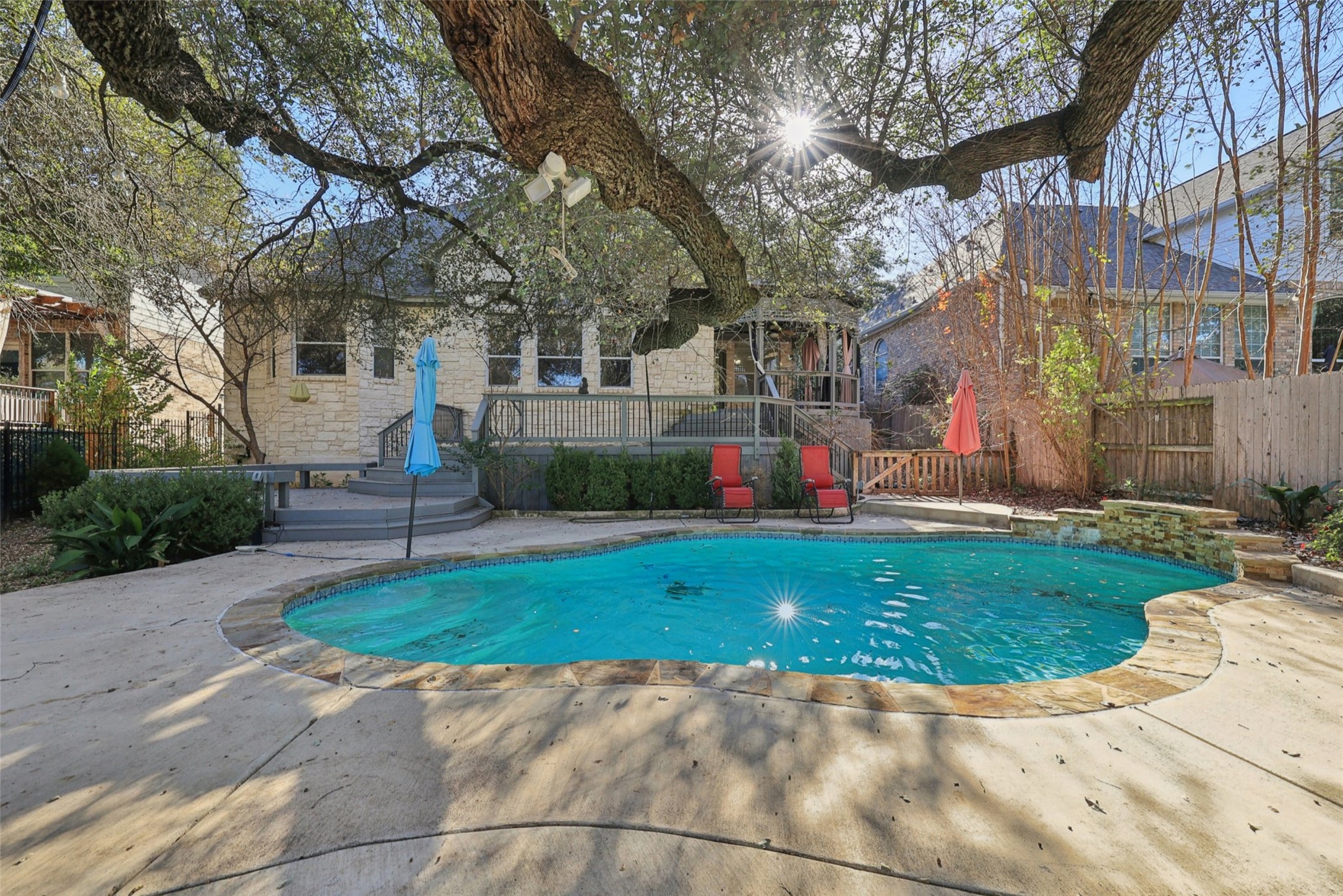 2948 Grimes Ranch Road Austin, TX 78732 - Photo 39 of 40 Freeform swimming pool featuring a stone surround, an integrated waterfall, and a spacious concrete patio.