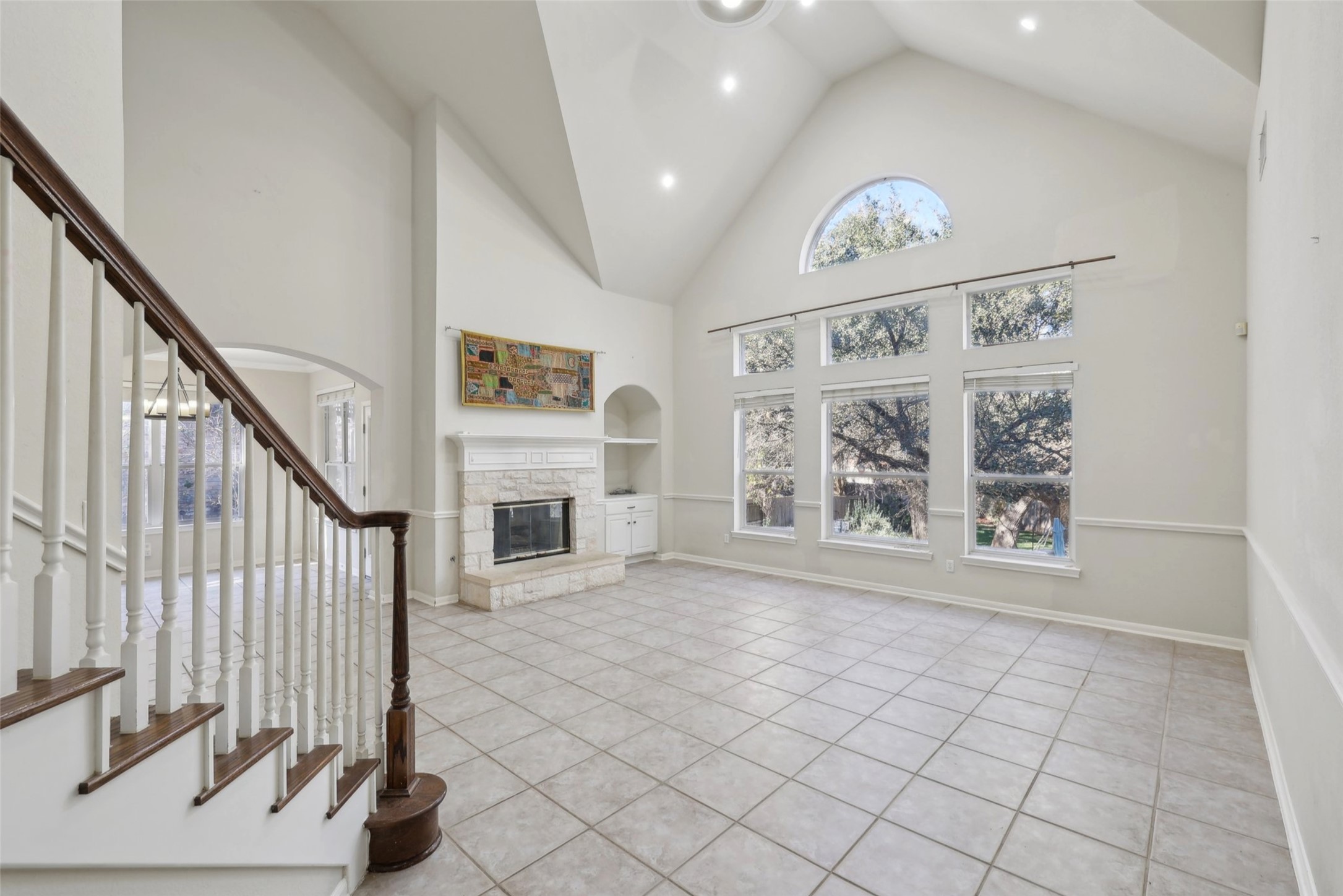 2948 Grimes Ranch Road Austin, TX 78732 - Photo 6 of 40 Unfurnished living room with healthy amount of natural light, a stone fireplace, built in shelves, tile patterned floors, and recessed lighting